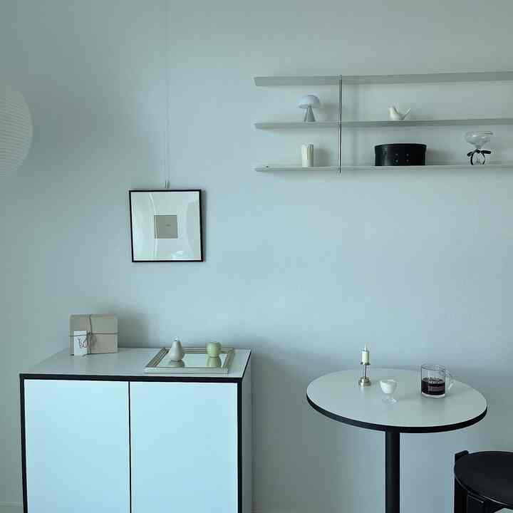 White and black-edged dining room featuring minimalist shelves and simple interior accessories creating a clean, modern space