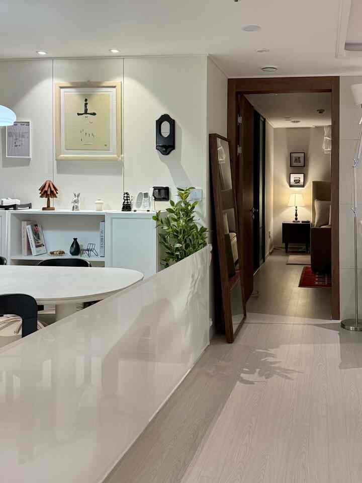 白い壁と木目調の床が調和したキッチン兼リビングスペース、透明なペットゲートが配置された清潔感のあるインテリア