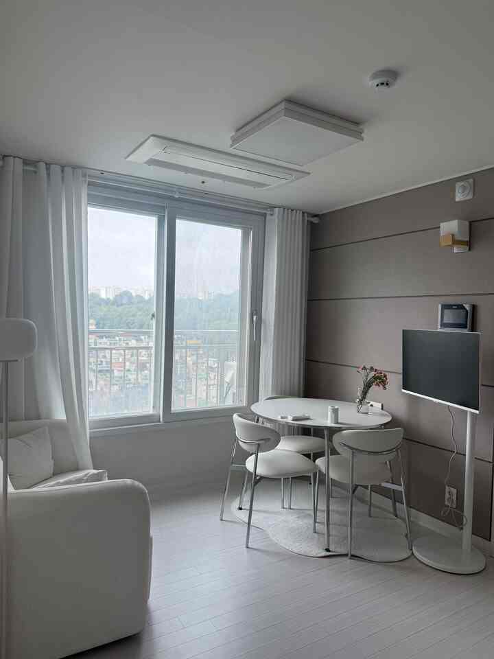 明るい白色調の8坪リビング、ミッドセンチュリーモダンのダイニングテーブルと2人掛けファブリックソファが配置されたモダンな空間