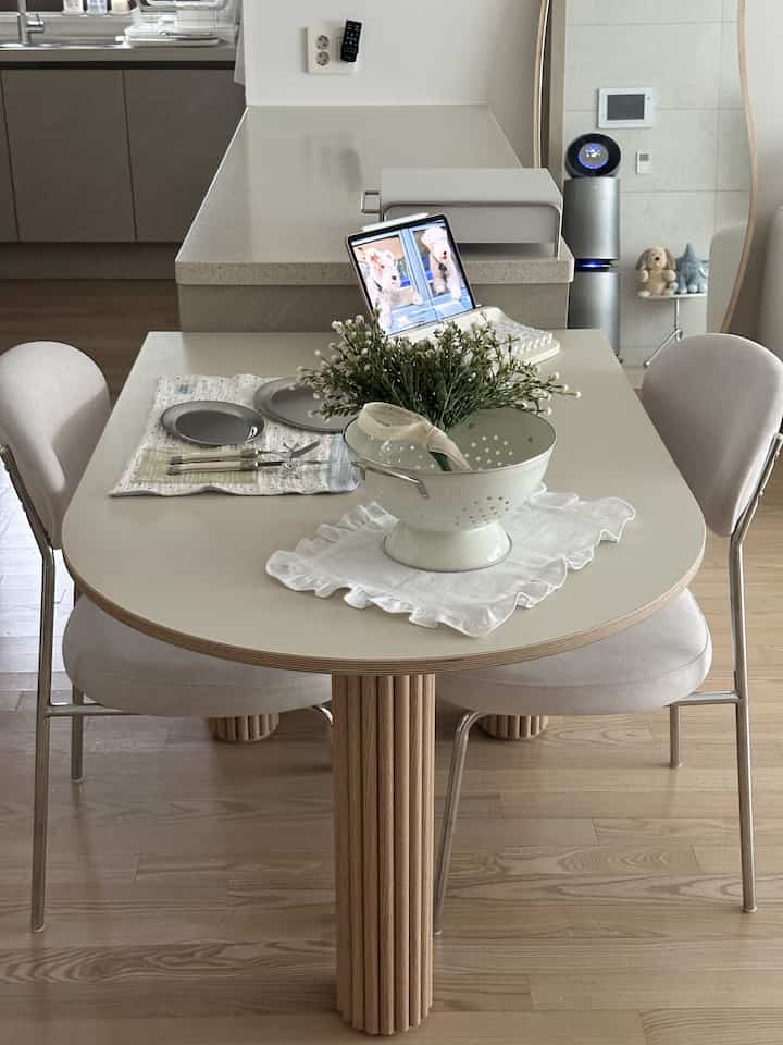 ベージュとウッドトーンが調和する2人用ダイニングスペース、清潔なトレイと花の飾りで雰囲気のあるホームカフェ空間