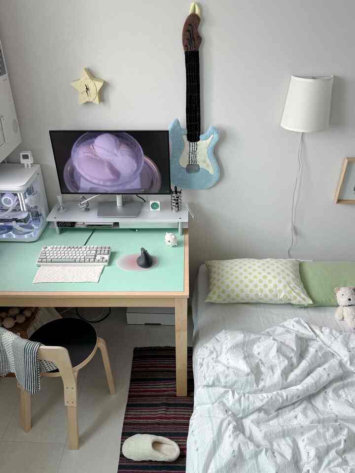 白い壁とミント色の机がある一人暮らしの寝室兼ホームオフィスの印象的な空間