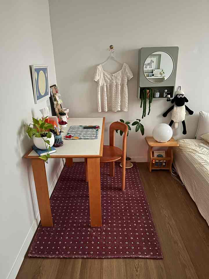 バーガンディ色のラグが敷かれた小さな書斎空間、木製の机と椅子が配置されていて、温かみのあるヴィンテージな雰囲気