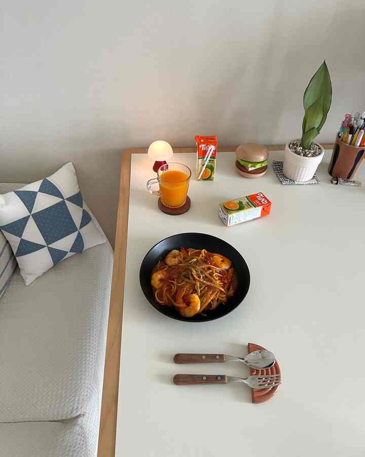 白と木目調の組み合わせが印象的なワンルームのテーブル空間、食事とおうちカフェアイテムが整然と配置された清潔感あるインテリア