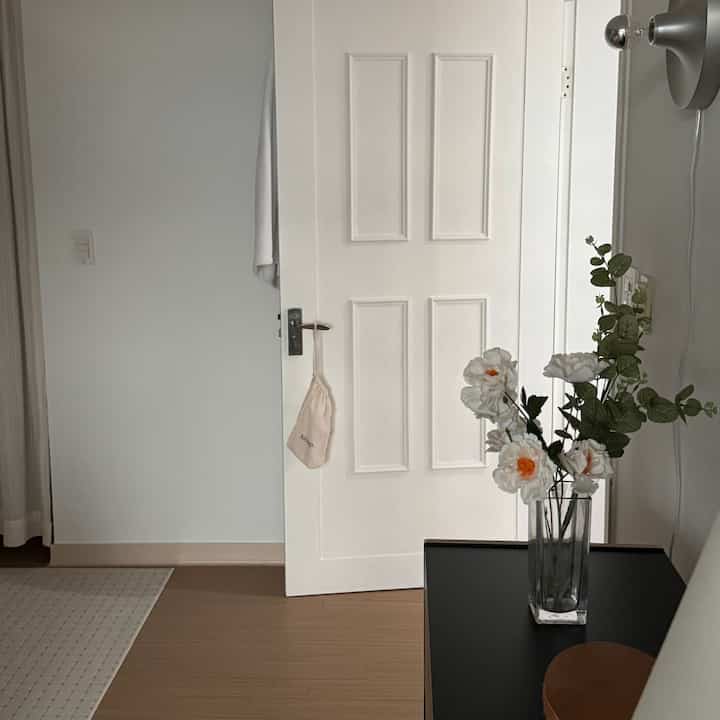 白と茶色のトーンの玄関、花瓶と植物が配置されたシンプルなインテリア