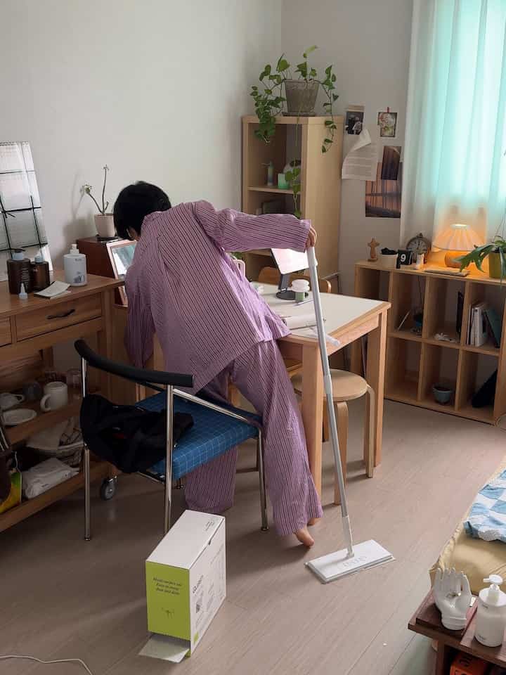 ナチュラルな色調のコンパクトな部屋、木製のデスクや本棚、ダイニングテーブルが配置された温かみのある空間