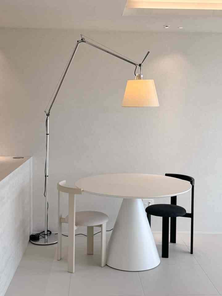 A monotone dining room in white and black tones featuring a clean round dining table and two chairs in a simple modern style