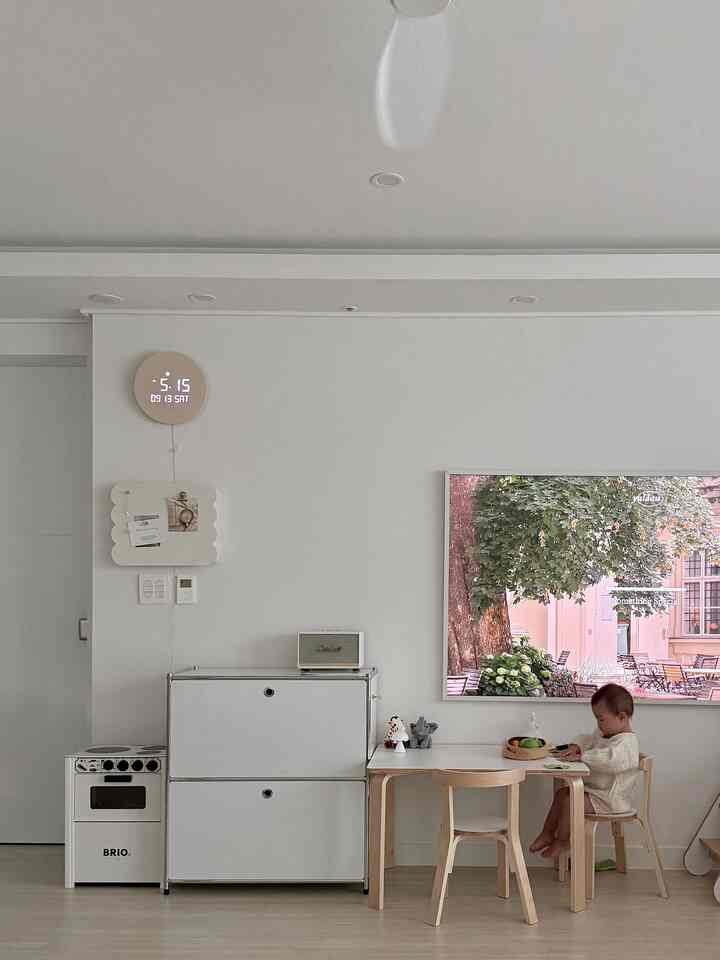 白とナチュラルな色調の子供部屋、子供用机と椅子が配置された明るくシンプルなインテリア