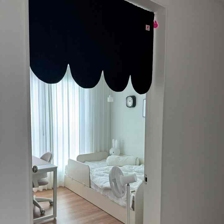 明るく白を基調とした子供部屋、子供用ベッドと机が配置されたミニマルなインテリア