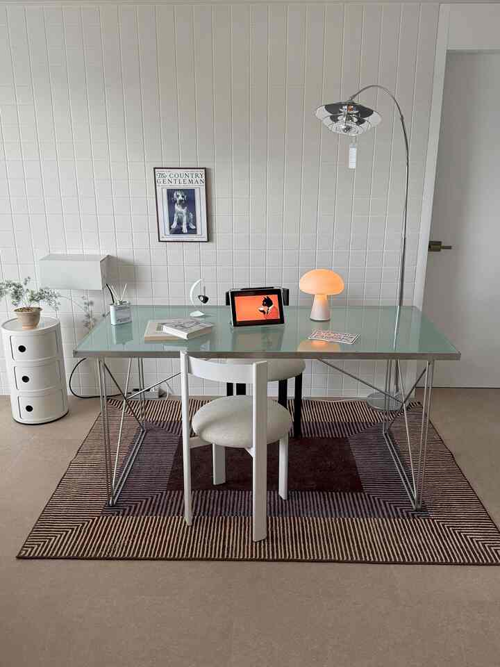 ベージュトーンのダイニングルーム、ガラステーブルと椅子、フロアランプとラグが配置されたミニマルな空間