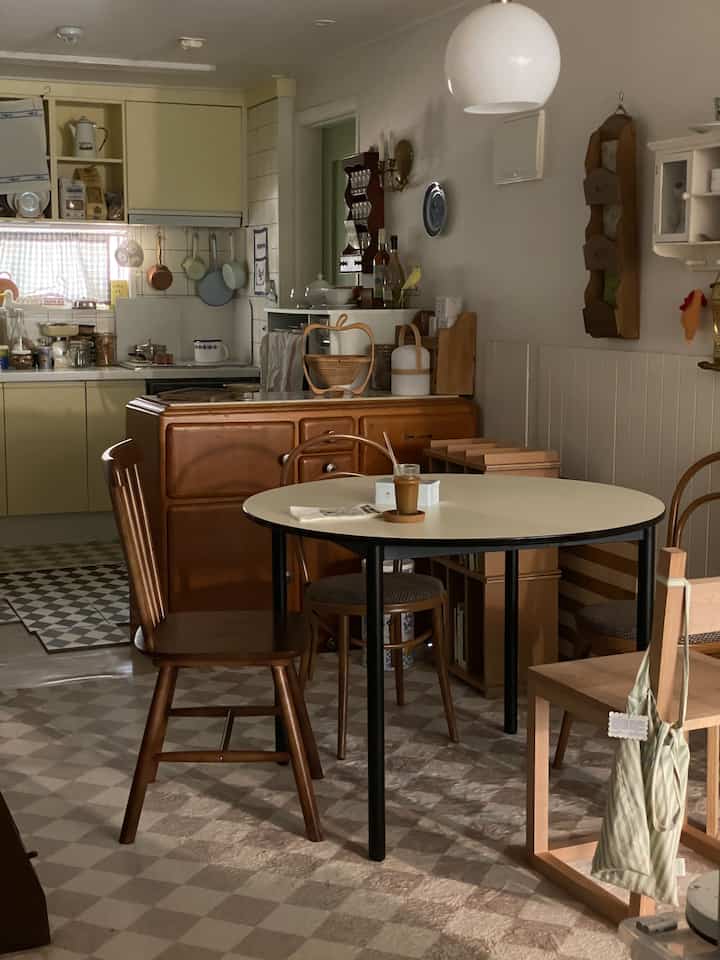 黄色と木目調が調和したキッチン、丸いダイニングテーブルが配置された雰囲気のあるヴィンテージ空間