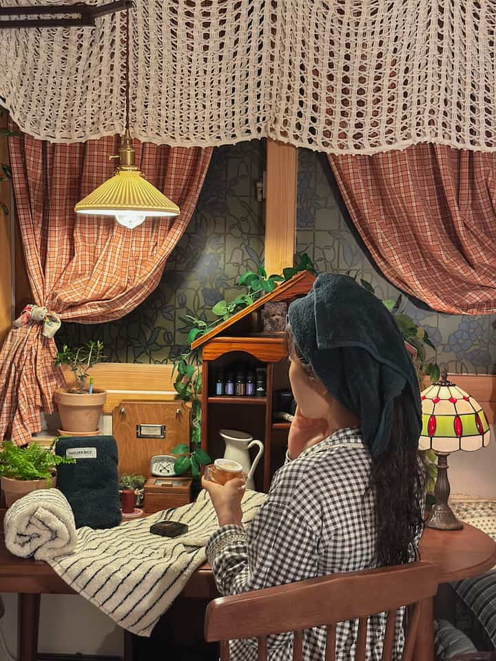 木目調とナチュラルカラーの寝室、チェック柄のカーテンと化粧台、タオルが配置された雰囲気のあるインテリア