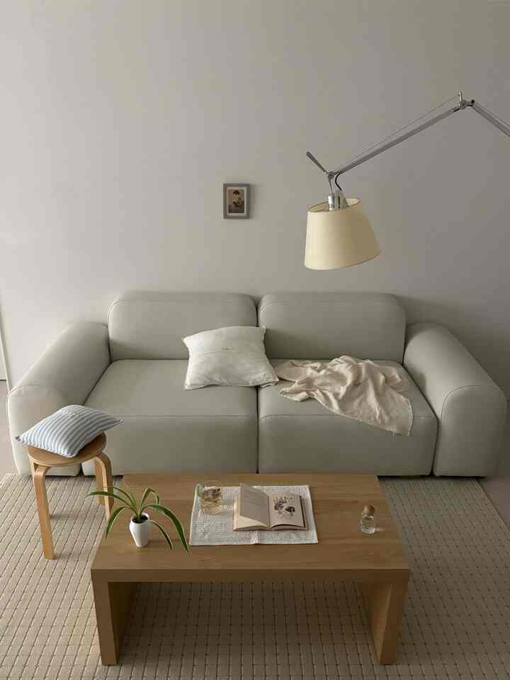 落ち着いたホワイトと木目調のリビング、ミニマルなレザーソファと木製コーヒーテーブル、アルテミデのフロアランプが配置された雰囲気のあるインテリア