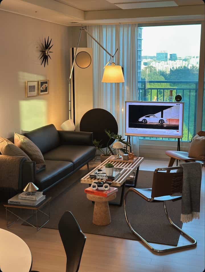 Mid-century modern living room in black and brown tones featuring an arch floor lamp and various furniture pieces with cozy atmosphere