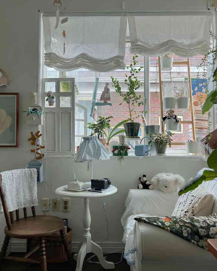 Bright white and wood-tone living room featuring multiple plants decorating the window, cozy vintage style atmosphere