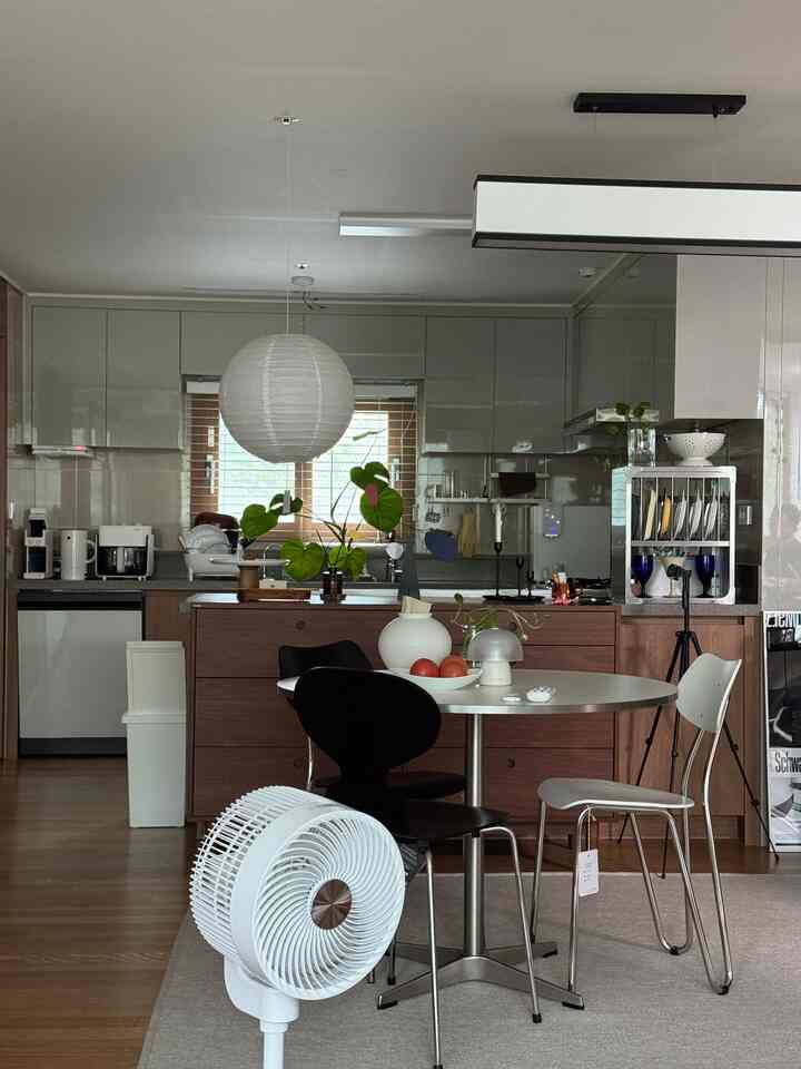 White and brown toned kitchen and dining area featuring a round dining table with chairs, creating a modern and warm atmosphere