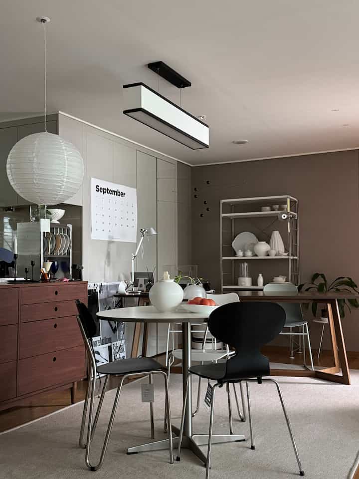 A calm white and wood-toned kitchen and dining area featuring a modern and natural ambiance with table and chairs
