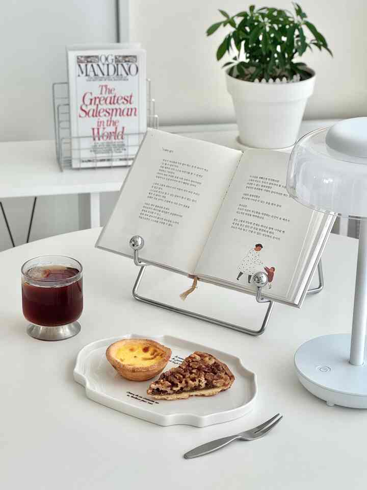 White-toned veranda space featuring table lamp, book stand, glass, and dessert plate creating cozy home cafe atmosphere