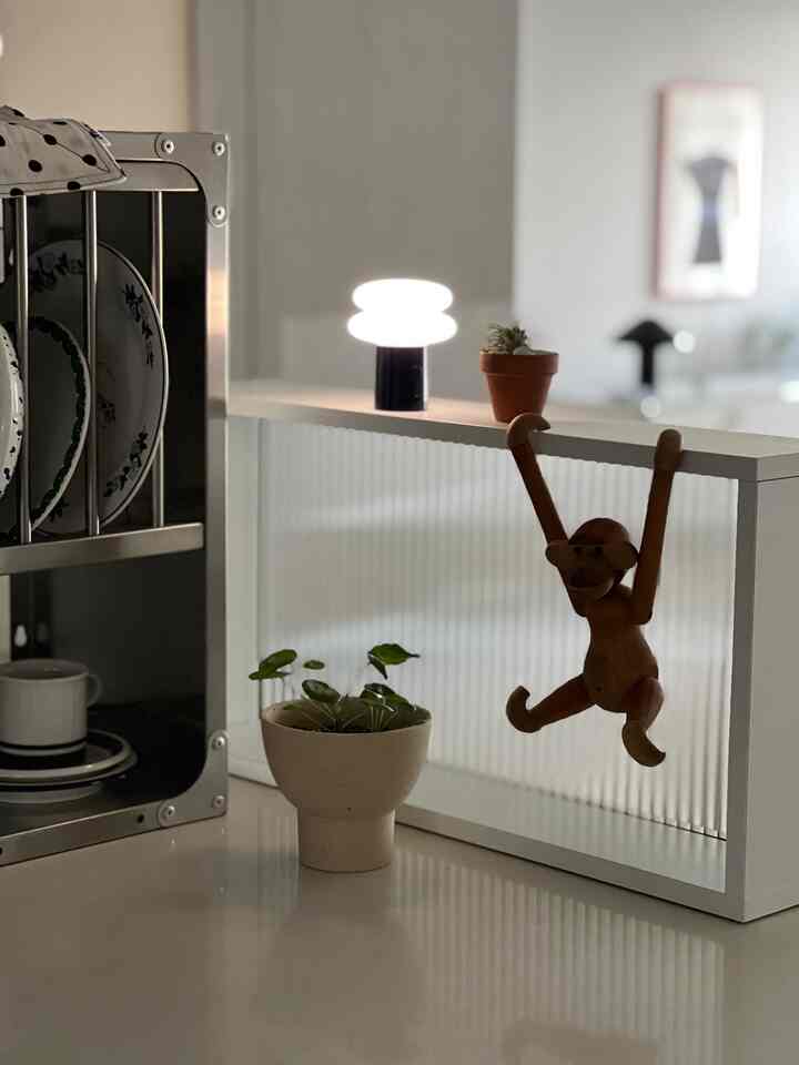 Natural-toned kitchen space featuring a dish rack, small lamp, and wooden objet with a clean minimalist vibe
