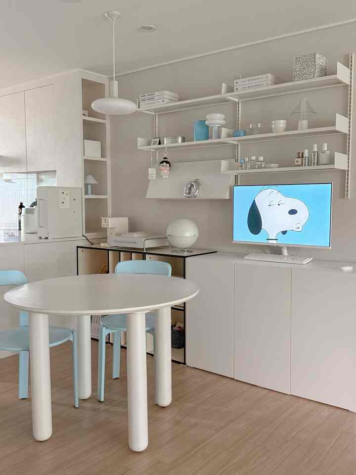 White-toned kitchen and dining area featuring blue chairs and neat shelving, creating a modern and natural home cafe interior