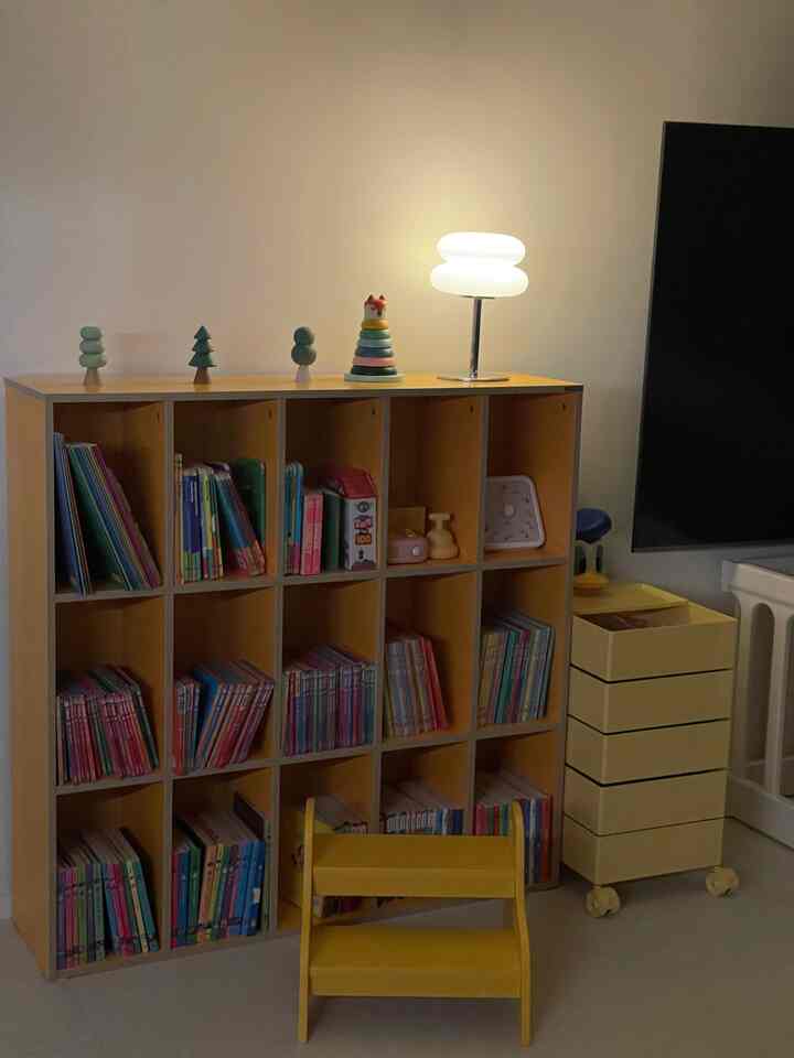 ナチュラルカラーの子供部屋、黄色い収納棚と本棚が配置された温かみのある空間