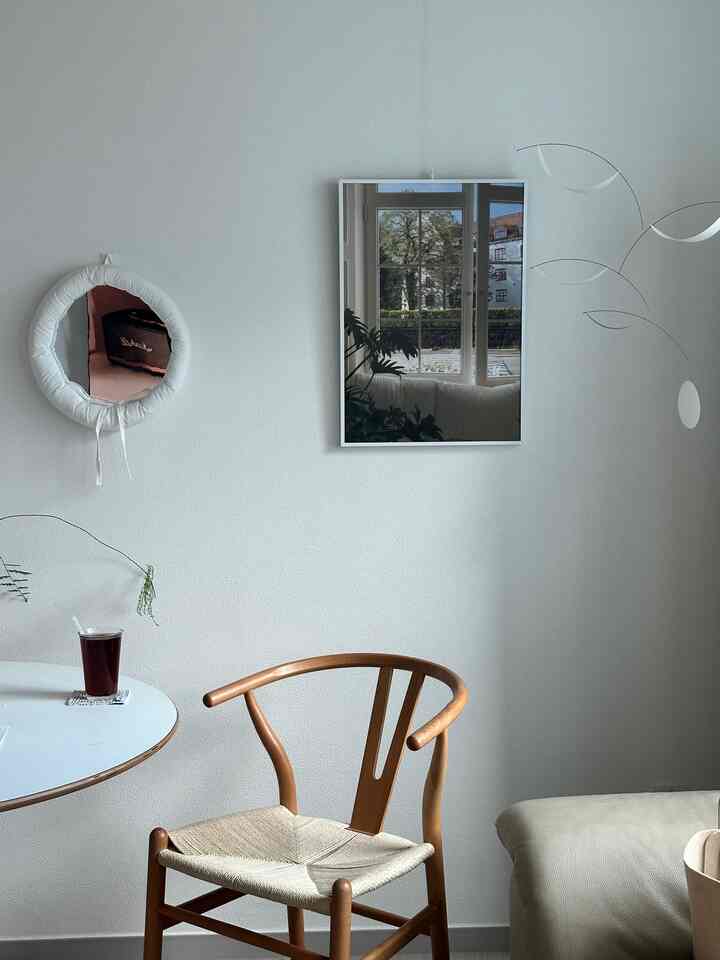 白い壁と木目調のダイニングチェアが配置されたナチュラルでミニマルなリビング空間