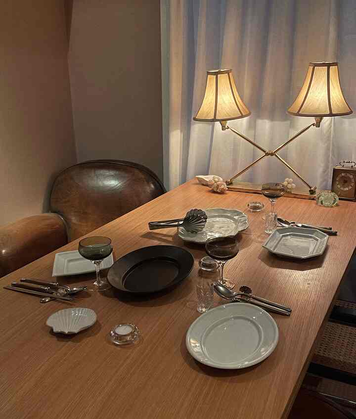 暖かいブラウンとホワイトのトーンのダイニングルーム、木製のテーブルとレザーの椅子、柔らかなテーブルランプが配置された雰囲気のあるインテリア