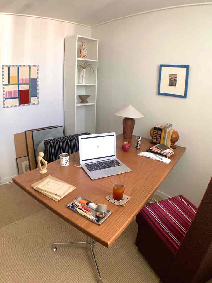 白い壁と木目調の机、本棚と額縁が配置された雰囲気のある書斎