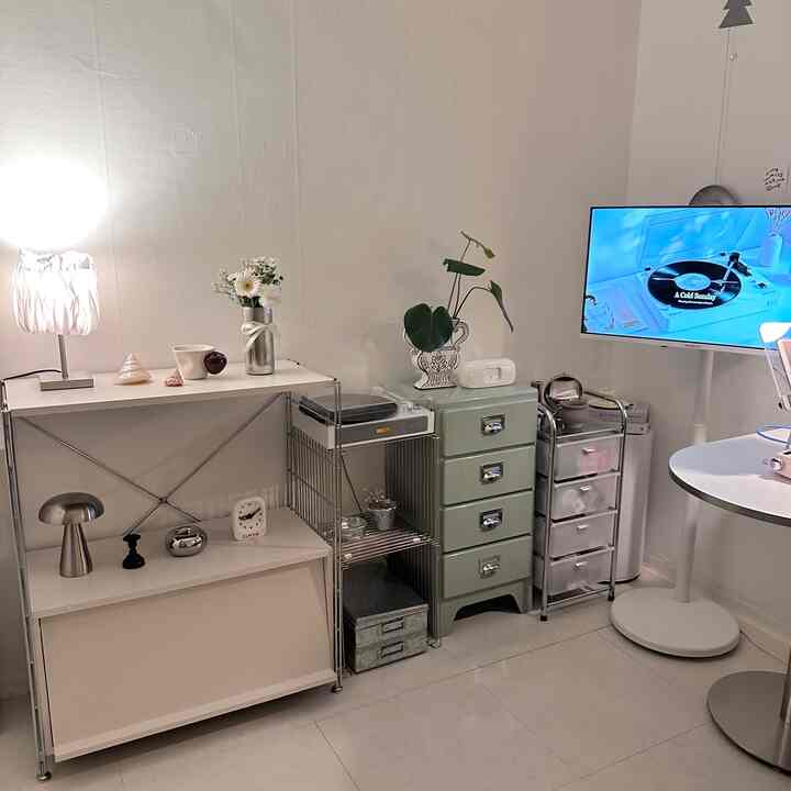 白とシルバーのトーンのリビング、ミッドセンチュリーモダンの引き出しとレトロなターンテーブルが配置された清潔感のある収納空間