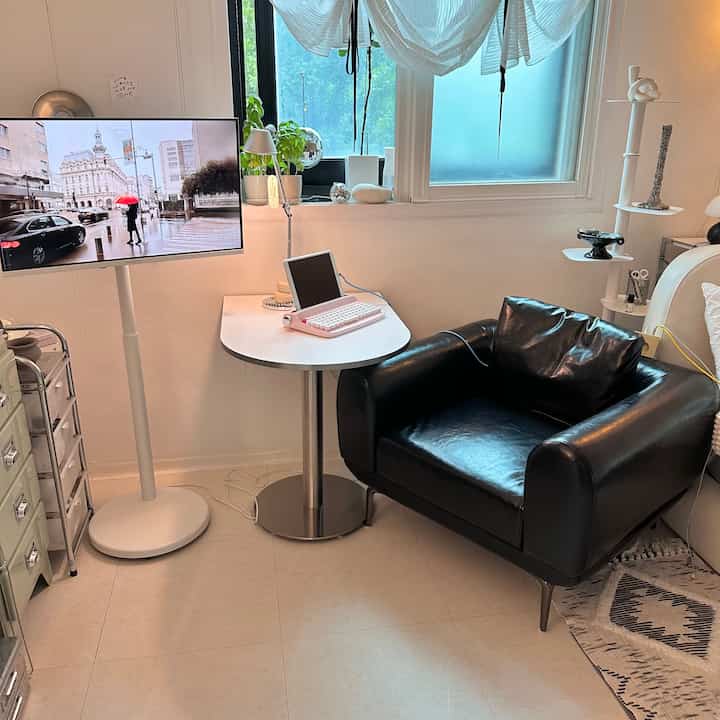 白い壁とテーブル、黒い革のアームチェアが配置されたコンパクトなホームオフィス空間