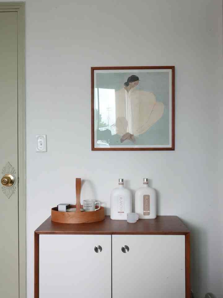 白と茶色のトーンの玄関空間、収納キャビネットと額縁が配置されたモダンなインテリア