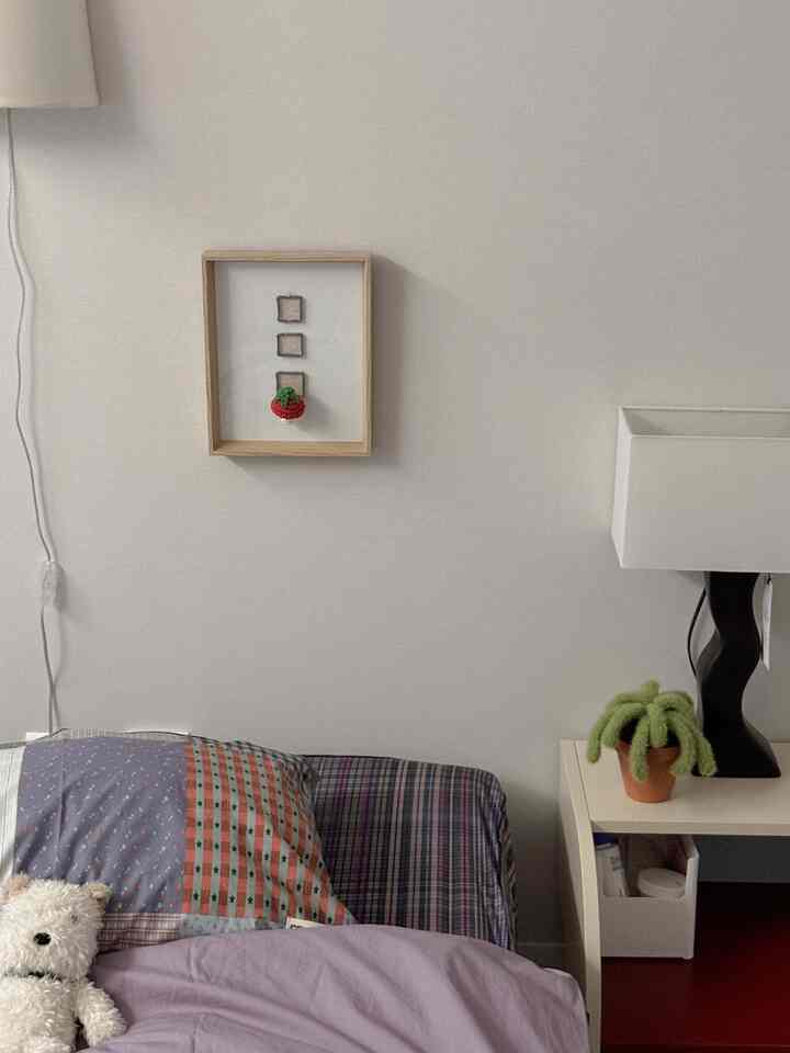 ライトグレーの壁と白いナイトスタンドが配置され、紫のスローのベッドが印象的なコンパクトな寝室