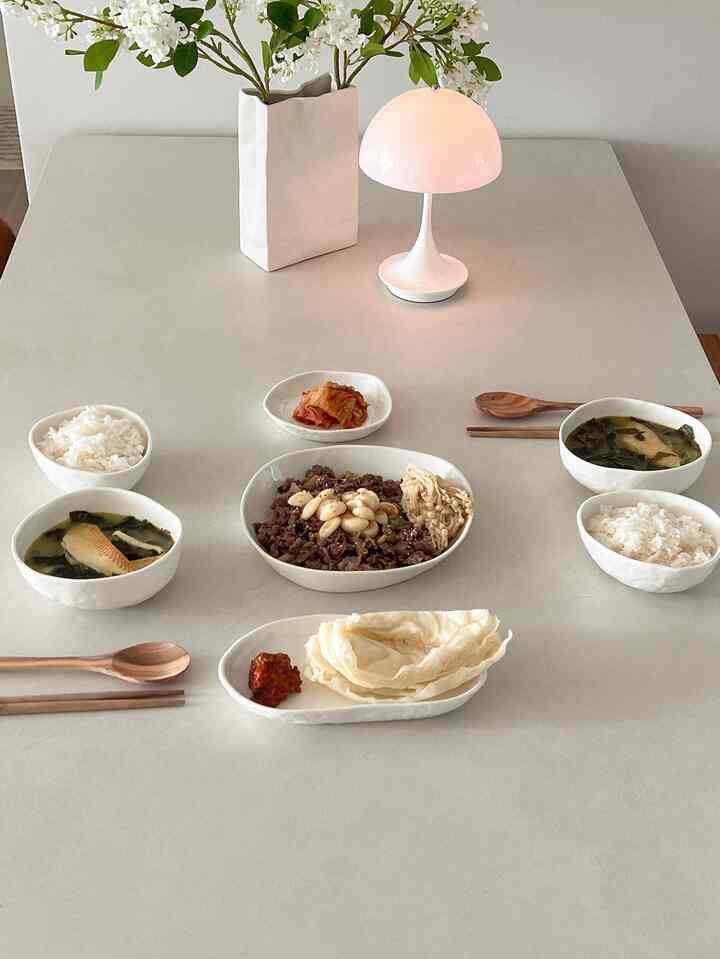 白とベージュの色調のダイニング、ミニマルなダイニングテーブルとテーブルランプが配置された印象的な空間