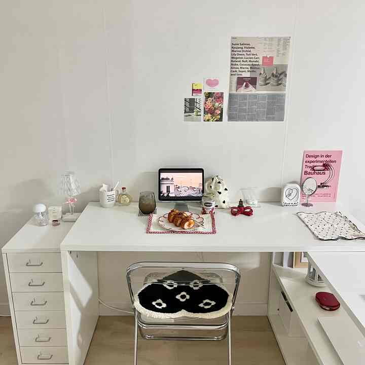 Simple home office space featuring white and transparent chair, neat desk, and posters on white wall with clean decor