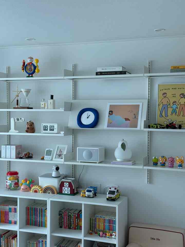 ホワイトトーンの子供部屋、おもちゃと本棚が配置された清潔でミニマルな雰囲気のインテリア