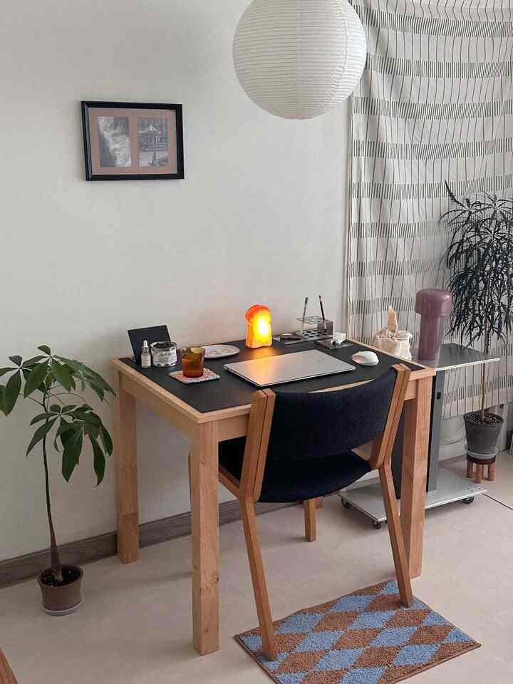 ナチュラルな色調のホームオフィス、木製のデスクと黒い椅子、緑の植物が配置された落ち着いた雰囲気のインテリア