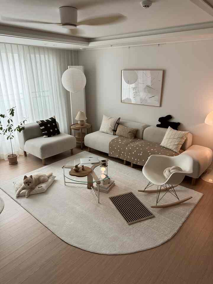 アイボリーとベージュのトーンのモダンなリビングルーム、モジュラーソファとユニークな形のラグが配置された居心地よく暖かい雰囲気のインテリア