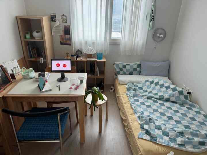 白い壁と木目調家具のある6畳の寝室、整ったデスクと寝具が配置された雰囲気のある空間