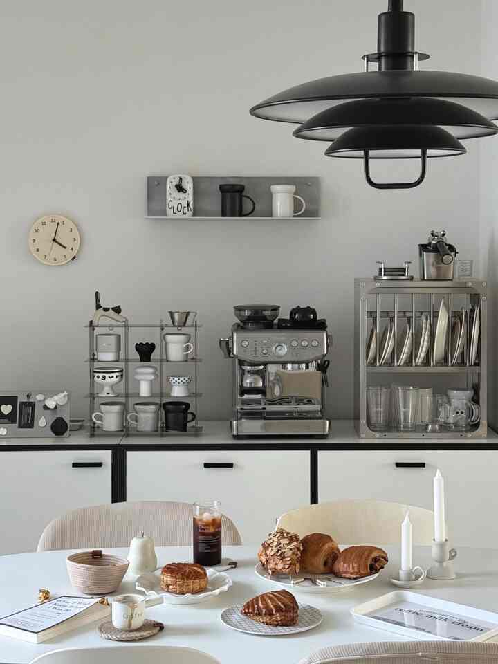 白とグレーを基調としたキッチン、コーヒーマシンとマグカップが配置された清潔感のあるモダンなおうちカフェインテリア