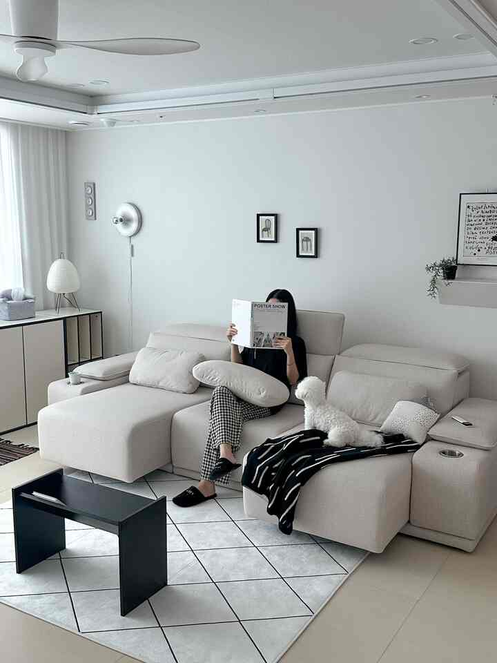 ベージュトーンのリビング、広いソファと小さな犬がいるシンプルモダンなインテリア