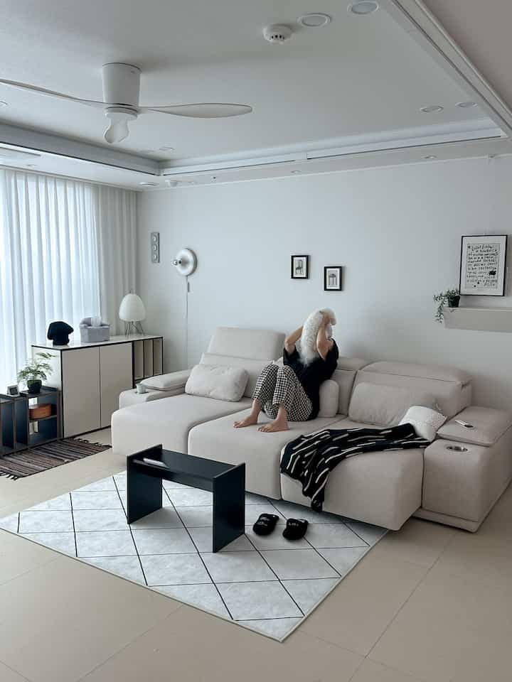 白と黒のモダンなリビング、セクショナルソファとパターンラグが配置された清潔感のある空間