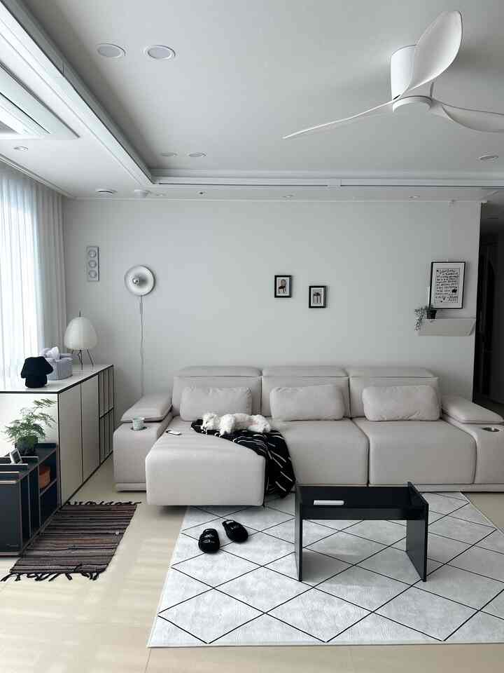 白い壁とベージュのソファが配置された居心地の良いリビング、ソファの上に犬が休んでいてモダンでミニマルな雰囲気のインテリア