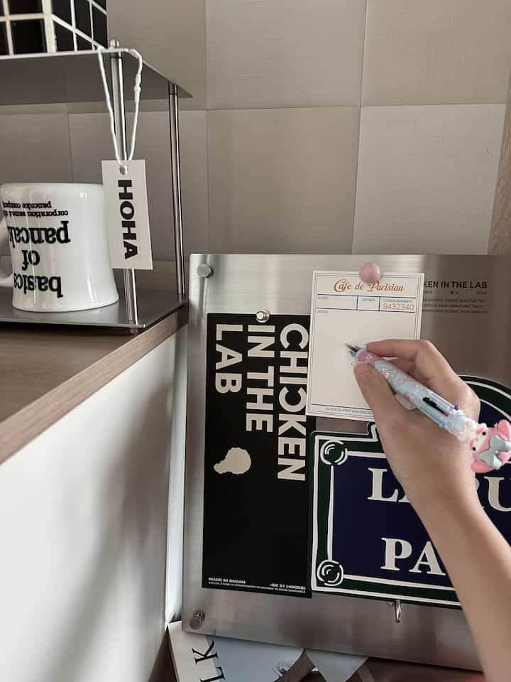 白い背景とシルバーの金属ボードがある空間、マグカップとメモが置かれた印象的なインテリア