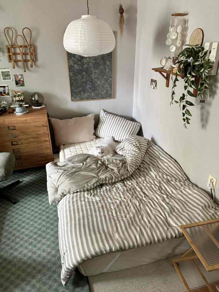 ベージュとグリーンの色調の寝室、木目調収納と植物が配置されたナチュラルモダンなインテリア