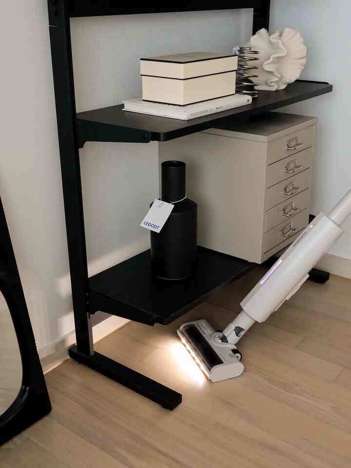 白と茶色の色調の玄関、黒い棚とベージュのドレッサーが配置されたミニマルでモダンな印象的なインテリア