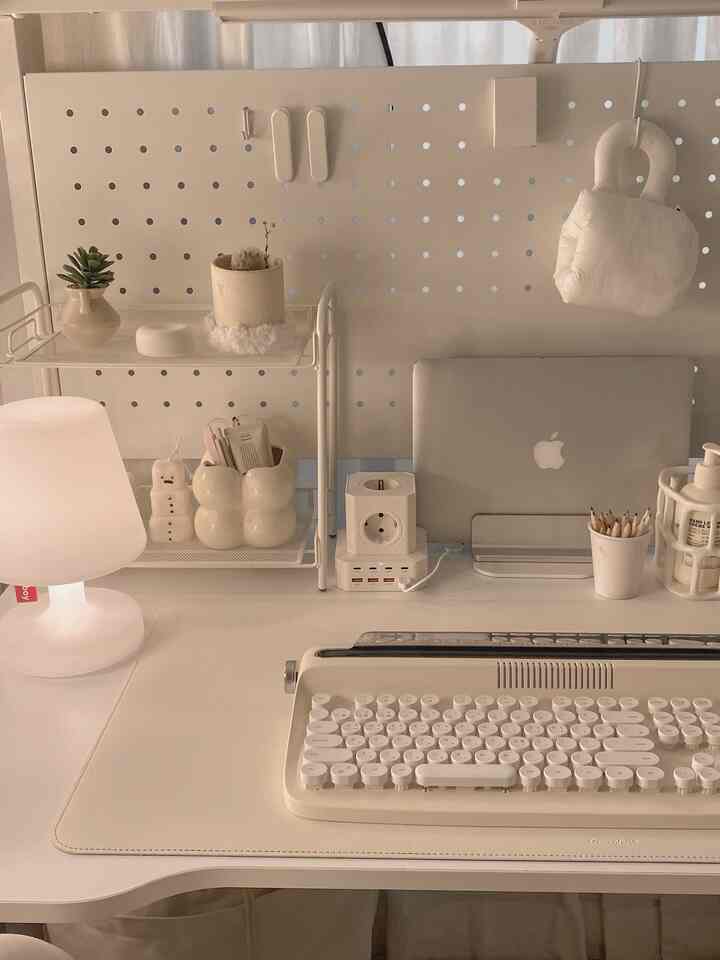 ホワイトとナチュラルカラーのホームオフィス、キーボードとノートパソコン、テーブルランプが配置された雰囲気のある作業空間