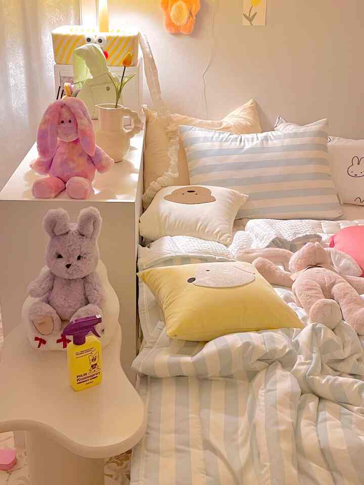 ピンクとホワイトのパステル調でまとめられた子供部屋、ぬいぐるみとクッションが配置された雰囲気のある寝室