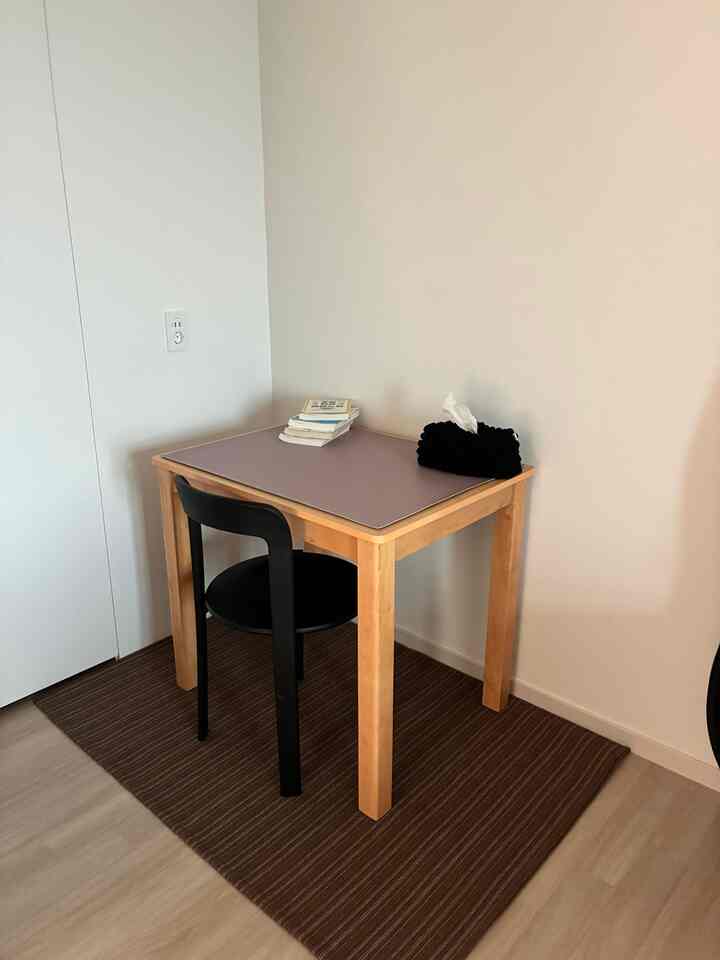 ナチュラルな木目調のダイニングテーブルと黒い椅子が配置されたコンパクトな二人暮らしの空間、シンプルで整ったレイアウト