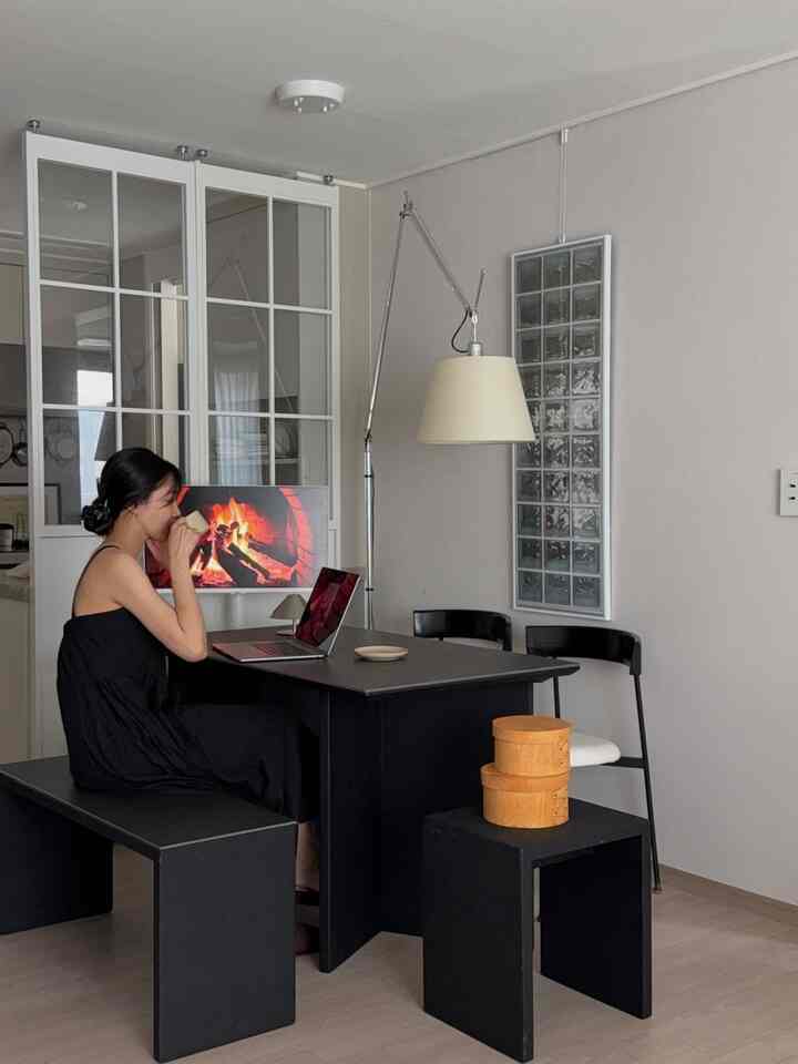 ブラック家具とベージュトーンが調和したダイニングルーム、ポーセリンテーブルとフロアランプが配置された雰囲気のあるインテリア