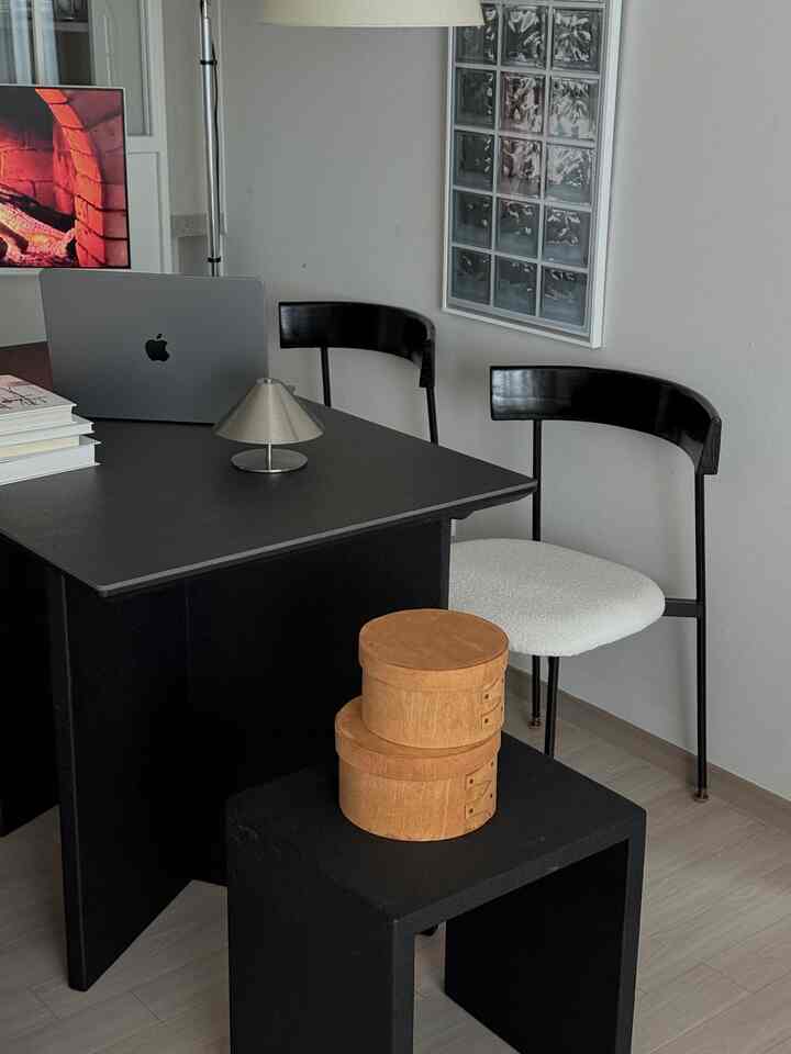 黒と白のトーンでまとめられたホームオフィス、黒いデスクとチェア、ノートパソコンと小さなライトが配置されたミニマルな空間