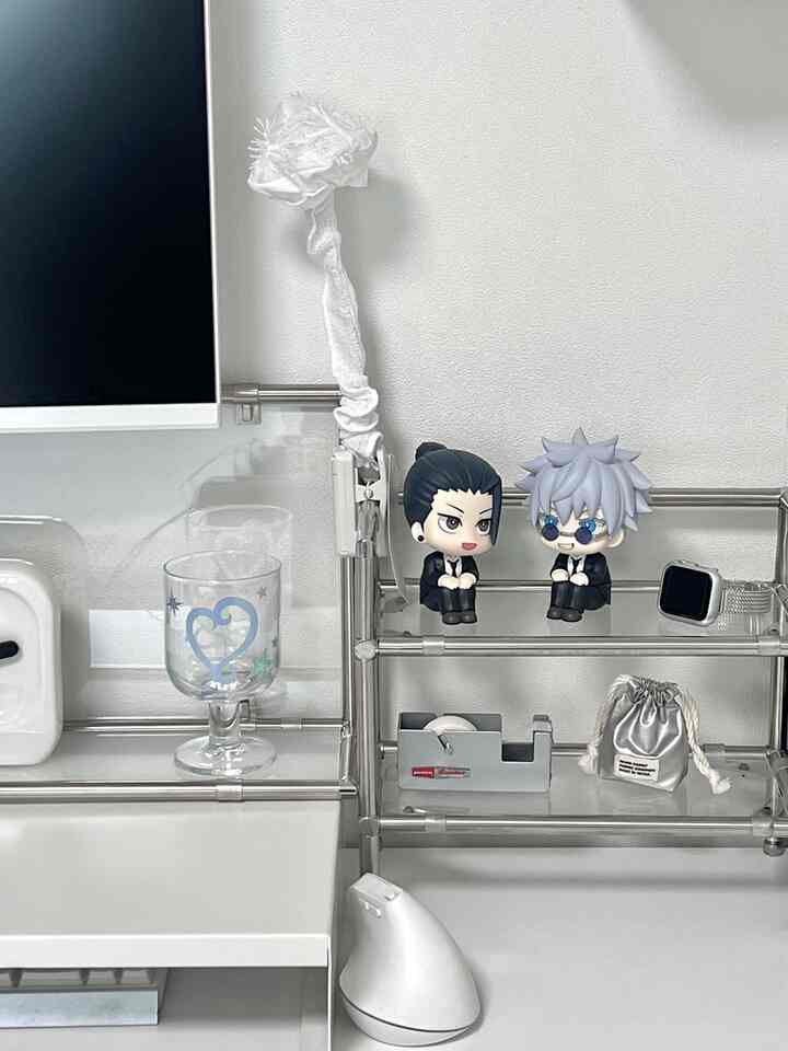 白とシルバーのトーンのデスク空間、モニタースタンドとフィギュアが配置された整った在宅勤務環境